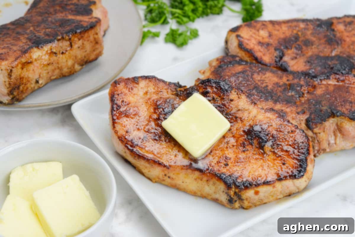 Blackstone'da Domuz Pirzolası 7 Kolay Adımda 10 finished blackstone pork chops plated on a white platter, topped with melting butter