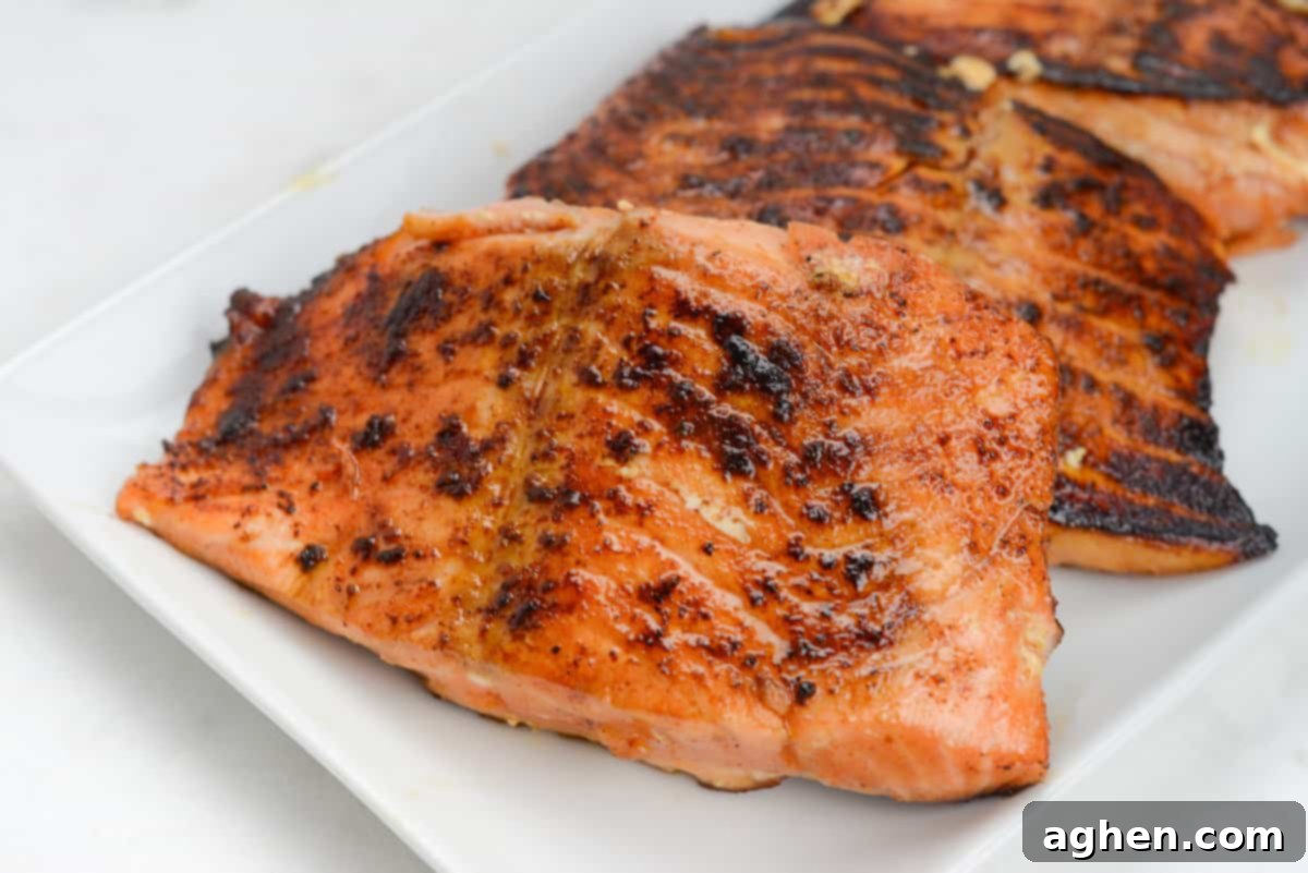 Three golden-brown, flaky salmon fillets, freshly cooked on a Blackstone griddle, perfectly ready to be served.
