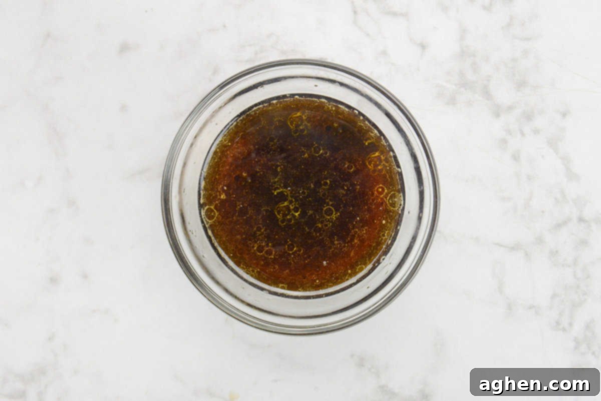 A sweet and savory blackstone salmon marinade, a rich amber liquid, mixed in a small clear glass bowl, ready for the salmon to be added.