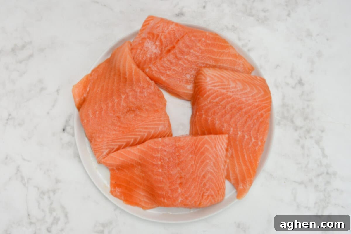 Raw marinated salmon fillets, expertly patted dry and glistening with a drizzle of olive oil, resting on a clean white plate, ready for seasoning.
