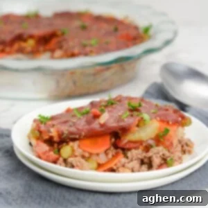 Plate filled with a portion of shipwreck casserole. To the side is a serving spoon with the casserole dish featured behind