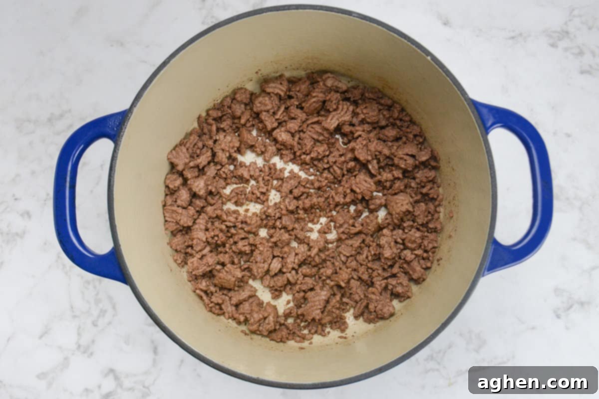 Guilt-Free Cowboy Casserole: A Weight Watchers Recipe You'll Love 4 A blue Dutch oven is shown with a cooked ground beef at the bottom