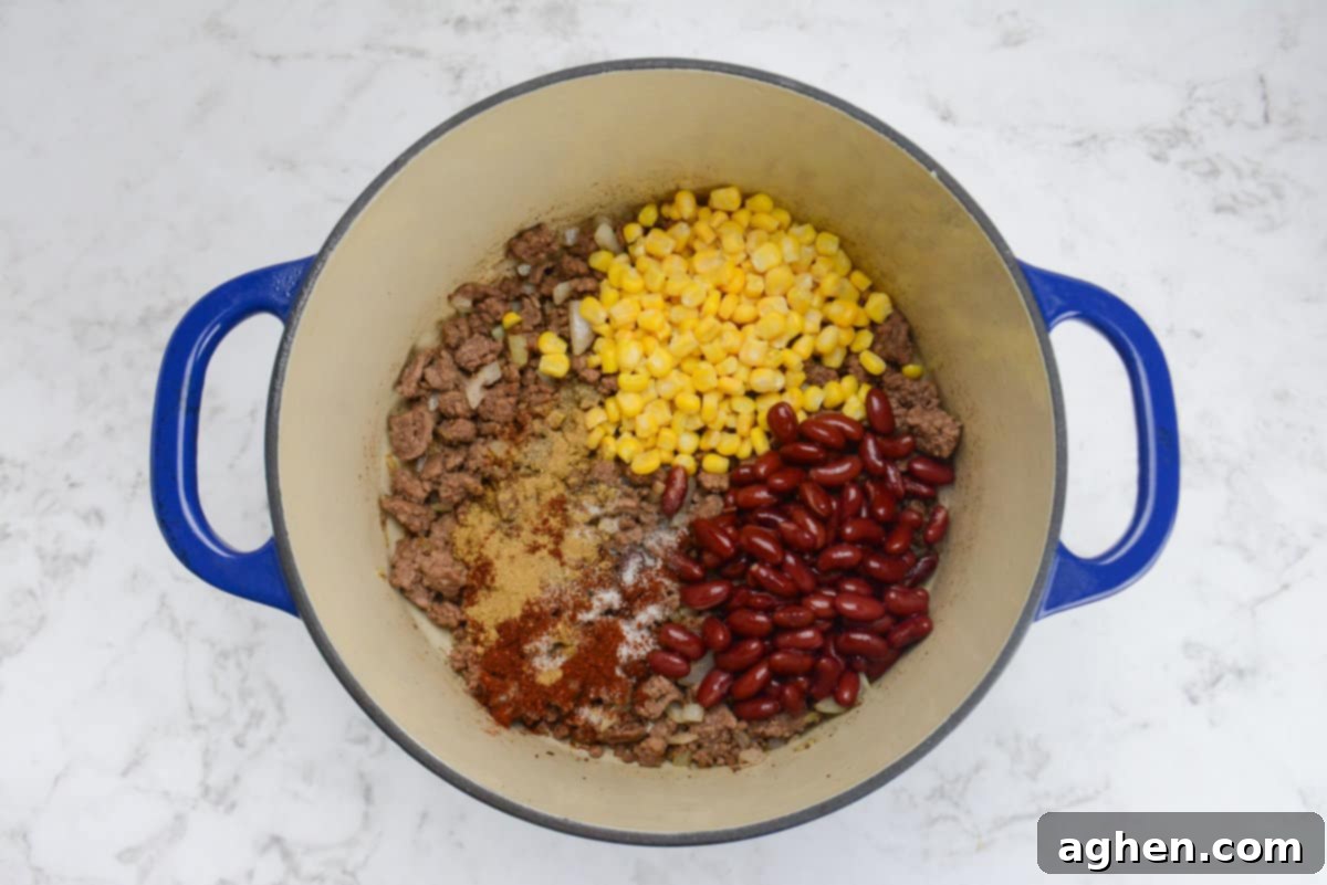 Guilt-Free Cowboy Casserole: A Weight Watchers Recipe You'll Love 6 A blue Dutch oven is shown with corn, beans and seasoning now added to the pot.