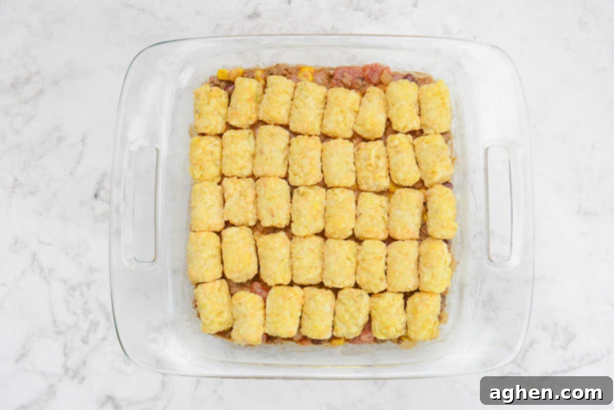 Guilt-Free Cowboy Casserole: A Weight Watchers Recipe You'll Love 10 A square casserole dish is shown filled with rows of tater tots topping the dish.