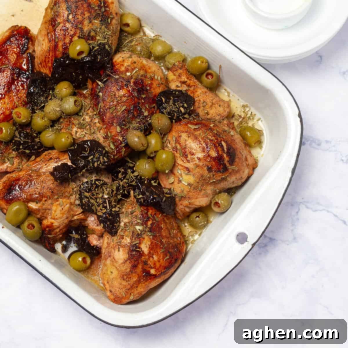 Scatter green olives and pitted prunes around the chicken in the baking dish