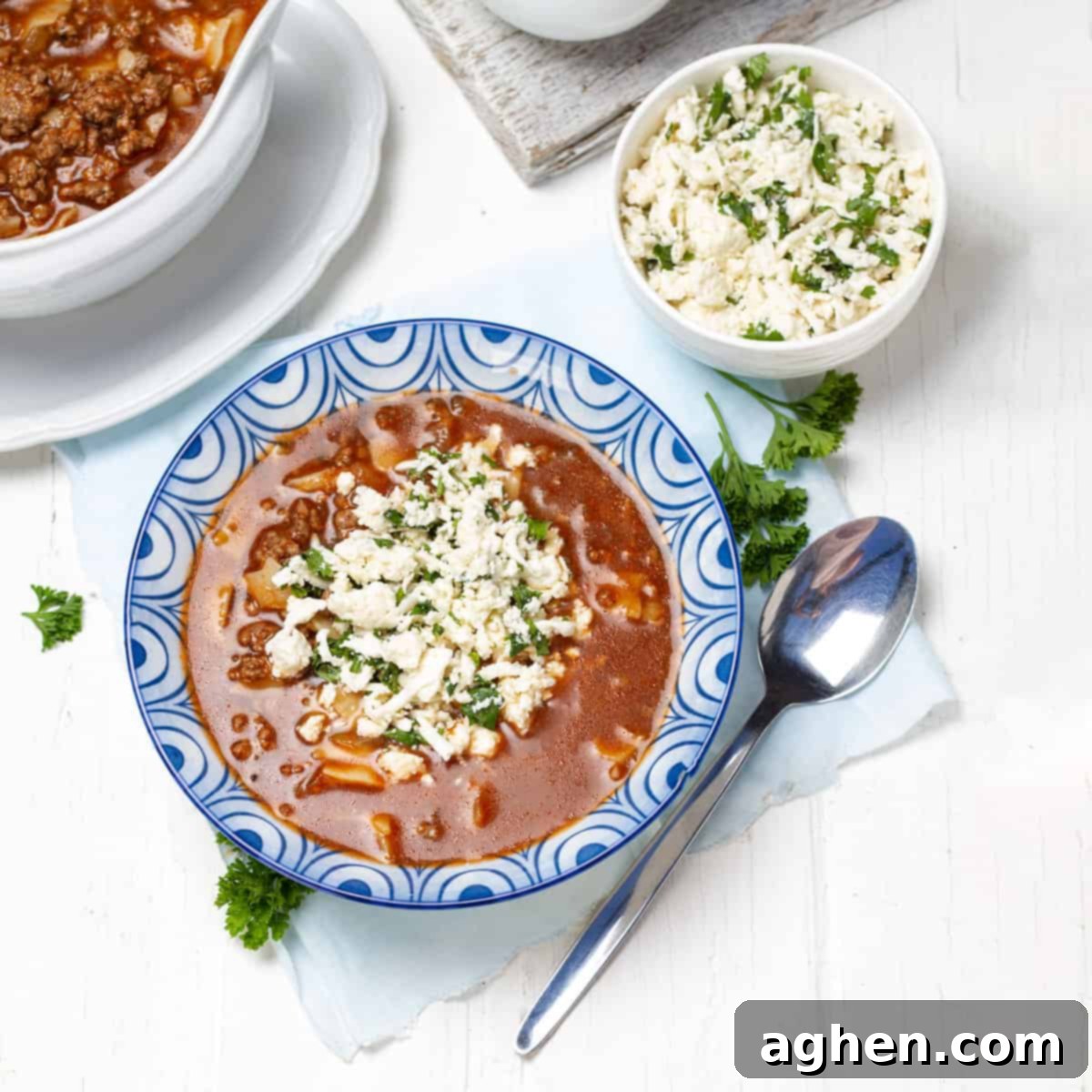 A warm and inviting bowl of healthy lasagna soup, garnished with fresh herbs and a swirl of creamy cheese topping.