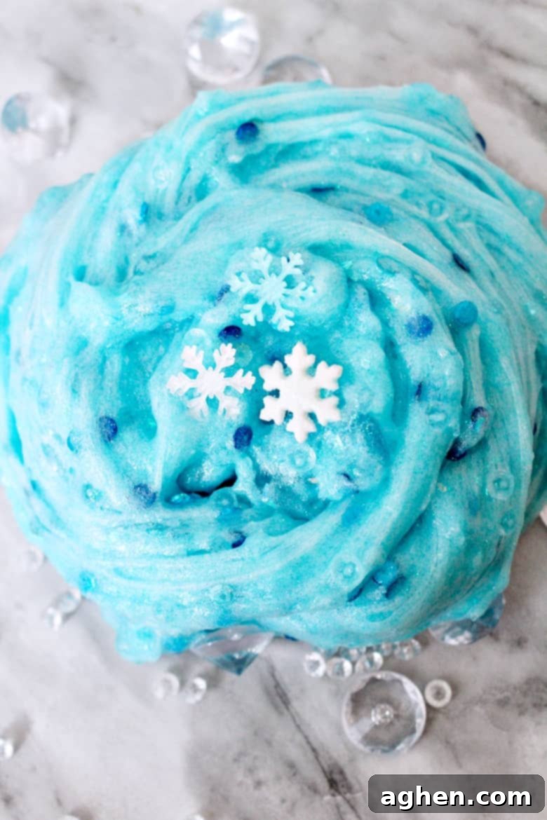 A child's hands stretching beautiful blue glittery Frozen snowflake slime, perfect for winter sensory play