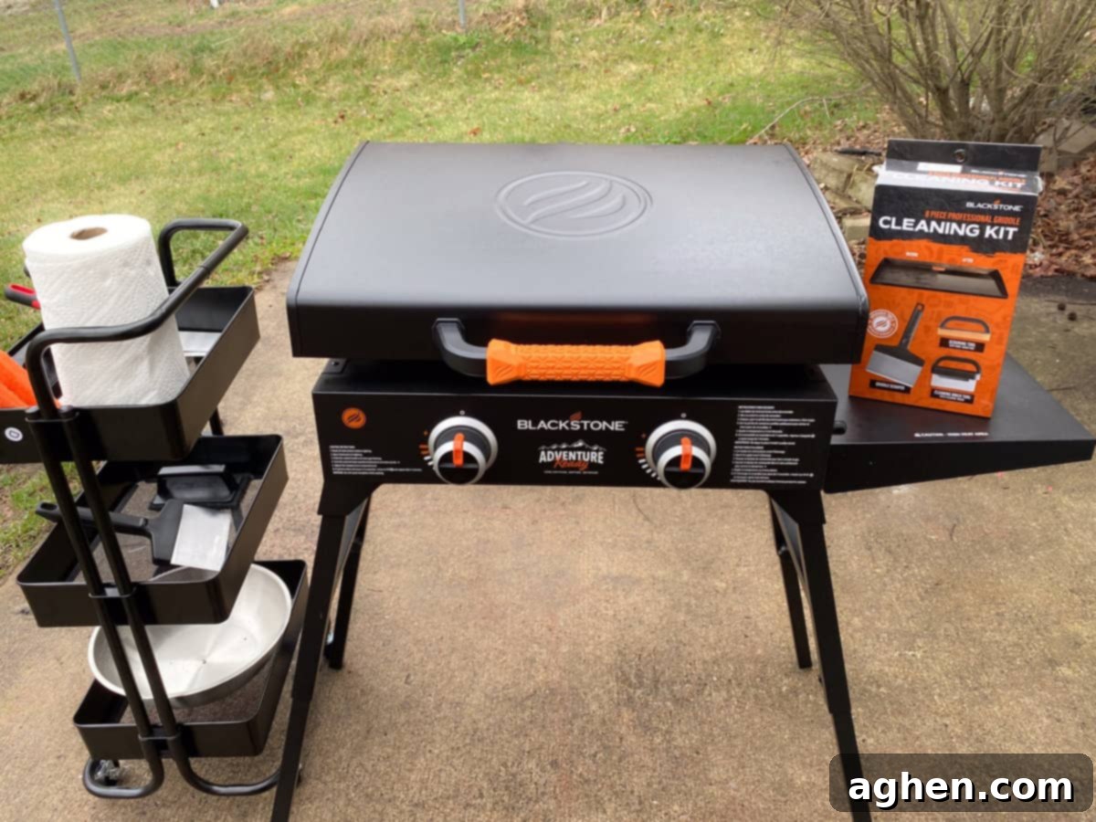 From Novice to Griddle Guru: 10 Hard-Earned Lessons After 3 Years on the Blackstone 5 A sleek Blackstone grill stands on a patio, ready for cooking. To its left, a small accessory cart holds essentials. On the right, a Blackstone cleaning kit box promises easy maintenance.