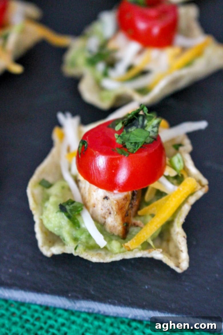 Close-up of individually assembled Chicken Nacho Bites with guacamole and fresh toppings