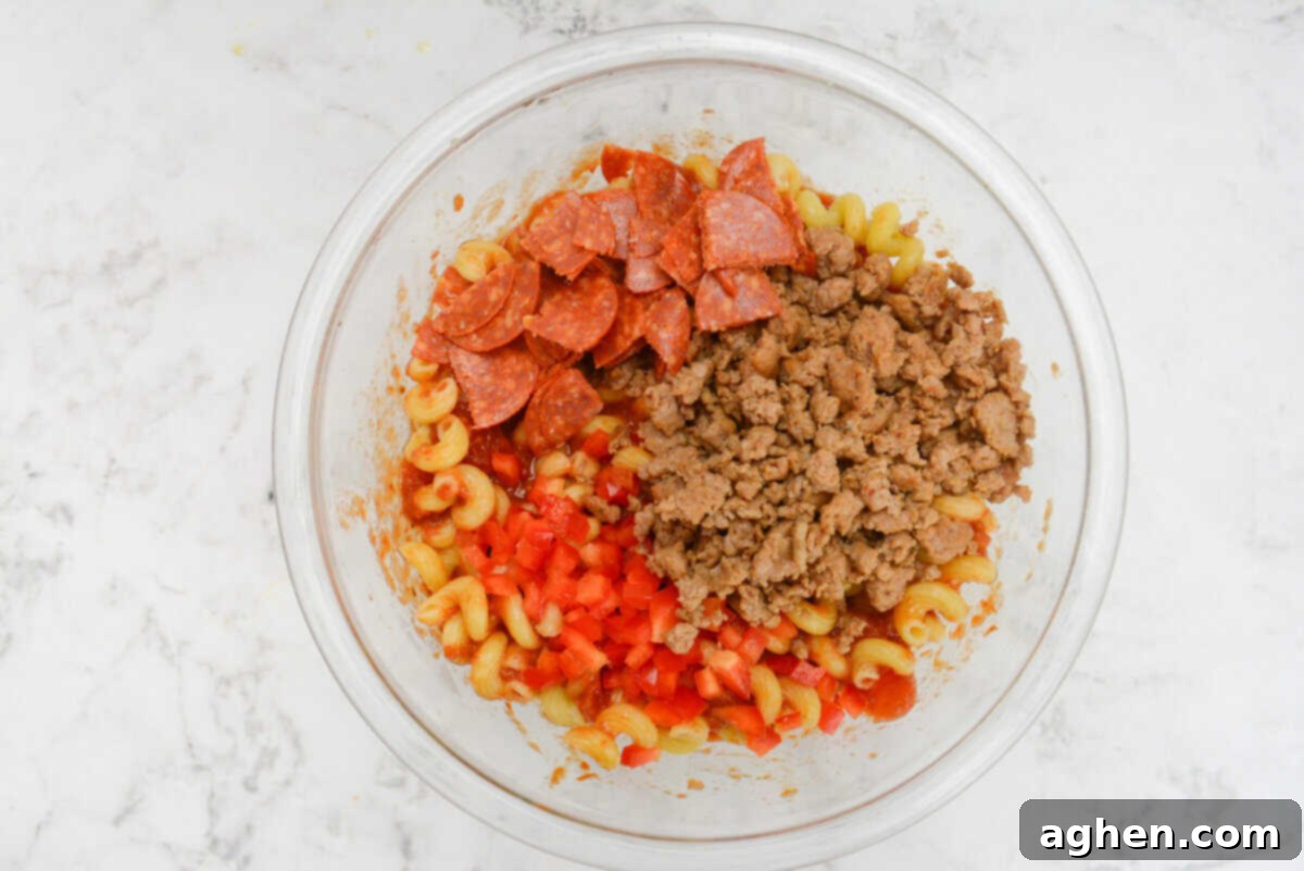 The bowl with the pasta and sauce is now topped with pepperoni, bell pepper and turkey sausage 