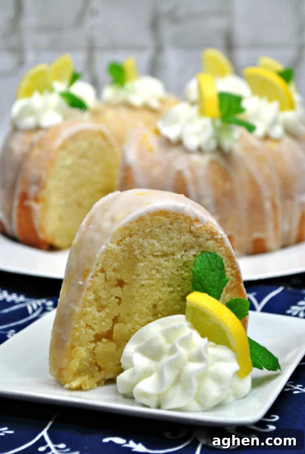 Close-up shot of a slice of moist lemon bundt cake, showing its tender crumb and the delicious lemon glaze drizzling down the sides.