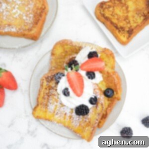 Unlock Legendary Blackstone French Toast with 7 Easy Steps 11 A plate filled with three slices French toast topped with whipped cream, berries, and powdered sugar. Two plates and berries sit to the side.