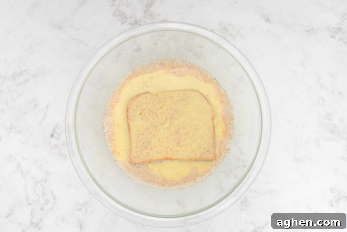 Unlock Legendary Blackstone French Toast with 7 Easy Steps 5 A large bowl with the whisked milk and egg mixture and a slice of bread placed into the center.