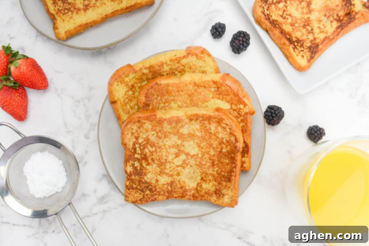 Unlock Legendary Blackstone French Toast with 7 Easy Steps 10 A plate of cooked Blackstone French toast in the center. Around it there is a sifter with powdered sugar, strawberries, blackberries, a glass of orange juice and two plates with more French toast