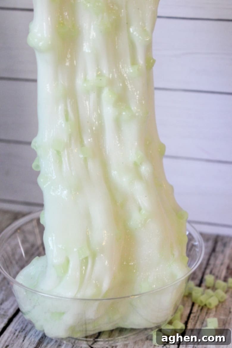 A child playing with green crunchy glow in the dark slime, stretching it to show the texture.