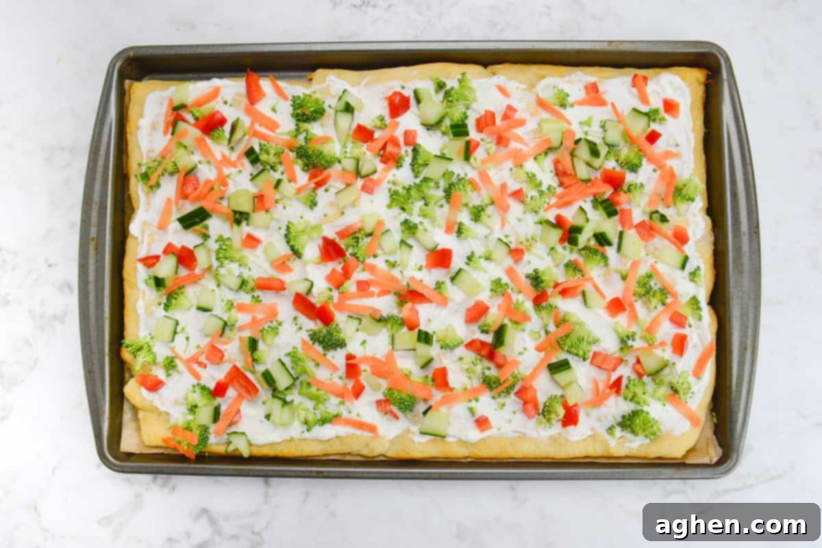 A baking sheet with the finished pizza topped with all of the chopped vegetables 