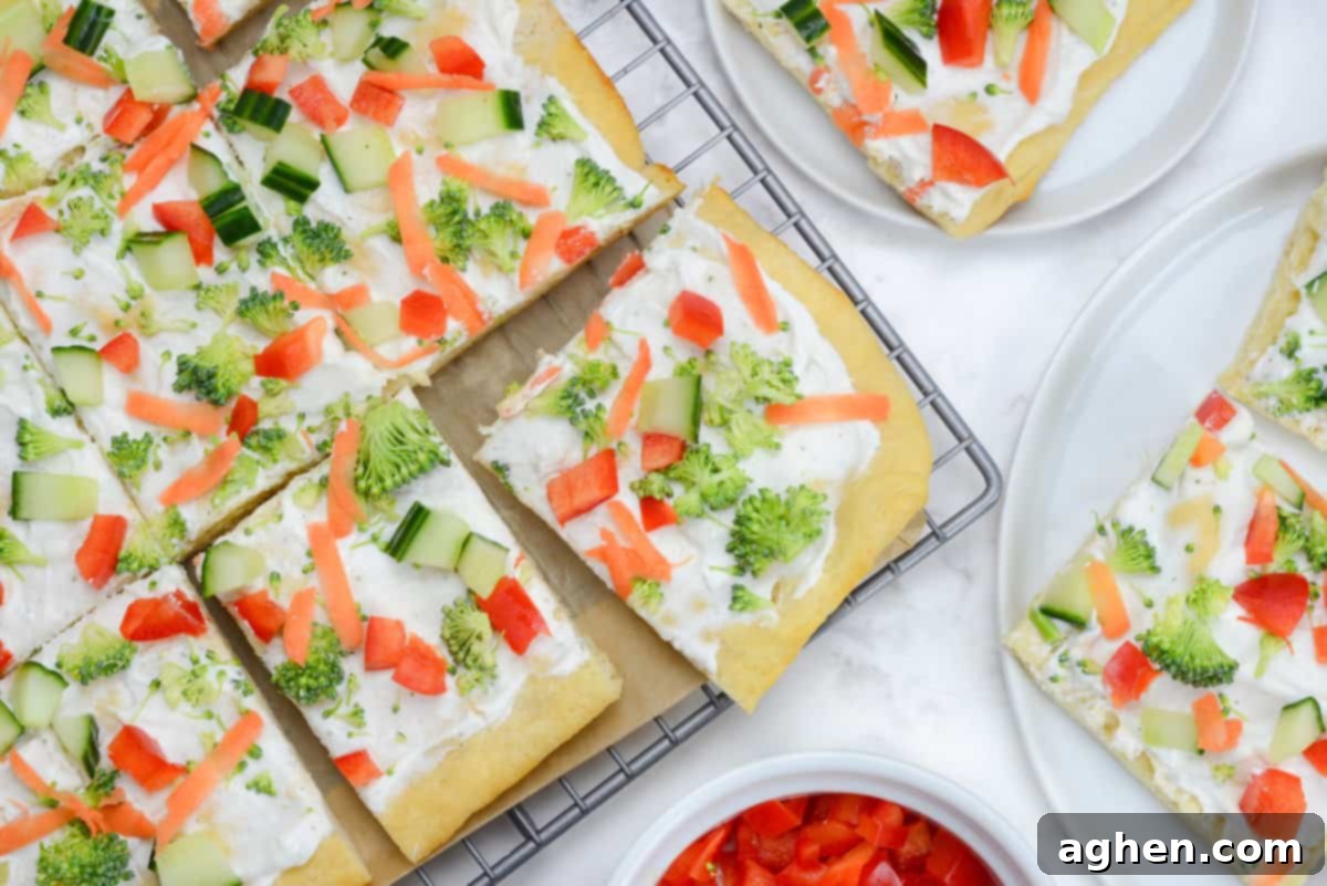The sliced finished pizza is placed on a parchment-lined cooling rack. Two plates sit to the side with slices of pizza. A small bowl with chopped red bell peppers is below.