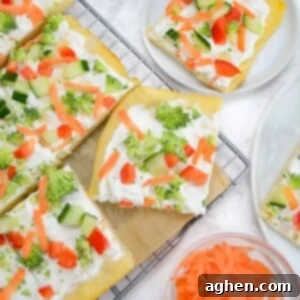 Four slices of cold veggie pizza are on a cooling rack lined with parchment. A small plate with one slice sits off to the side. A small bowl of shredded carrots is below.