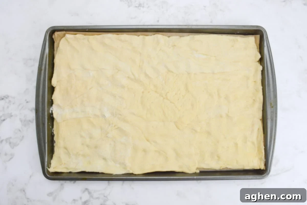A baking sheet lined with parchment and the dough pressed into a flat layer 