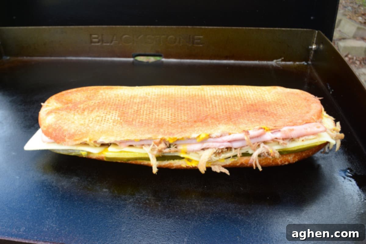 Öğle Yemeğiniz Asla Aynı Olmayacak: Blackstone Küba Sandviçi 11 Cuban sandwich expertly flipped on the Blackstone griddle, showing an even golden-brown crust on the first side, ready for the second side to cook.