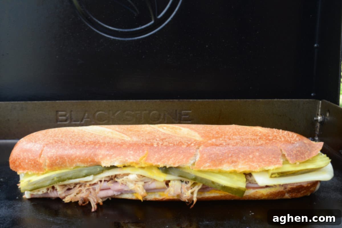 Öğle Yemeğiniz Asla Aynı Olmayacak: Blackstone Küba Sandviçi 12 Finished Blackstone Cuban Sandwich, perfectly pressed and toasted, sitting on the griddle ready to be sliced and served.