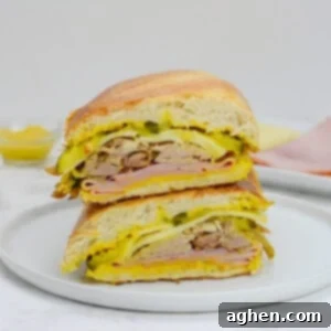 Öğle Yemeğiniz Asla Aynı Olmayacak: Blackstone Küba Sandviçi 13 Two halves of Blackstone Cuban Sandwich stacked on top of each other on a white plate, ready to be enjoyed.