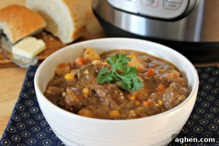A beautifully presented bowl of Instant Pot beef stew, garnished with fresh herbs, served on a navy blue placemat with slices of crusty French bread.