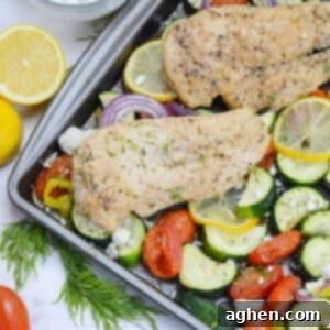 Effortless Delicious Weight Watchers Greek Sheet Pan Chicken 11 Close up of cooked Greek sheet pan chicken. Two pieces of chicken are on top of roasted vegetables in a sheet pan. A cut lemon and sprigs of dill are to the side.