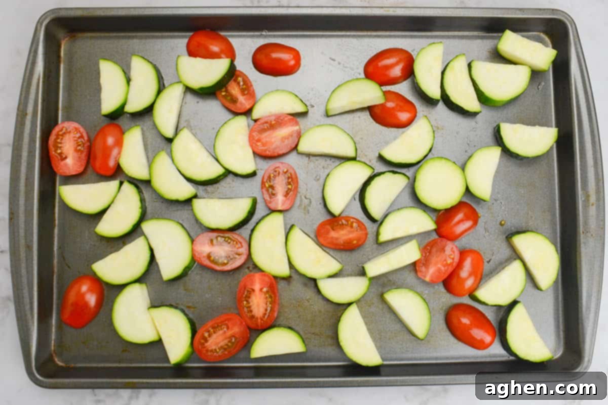 Effortless Delicious Weight Watchers Greek Sheet Pan Chicken 6 A sheet pan with halved cherry tomatoes and bite half-moon zucchini cuts