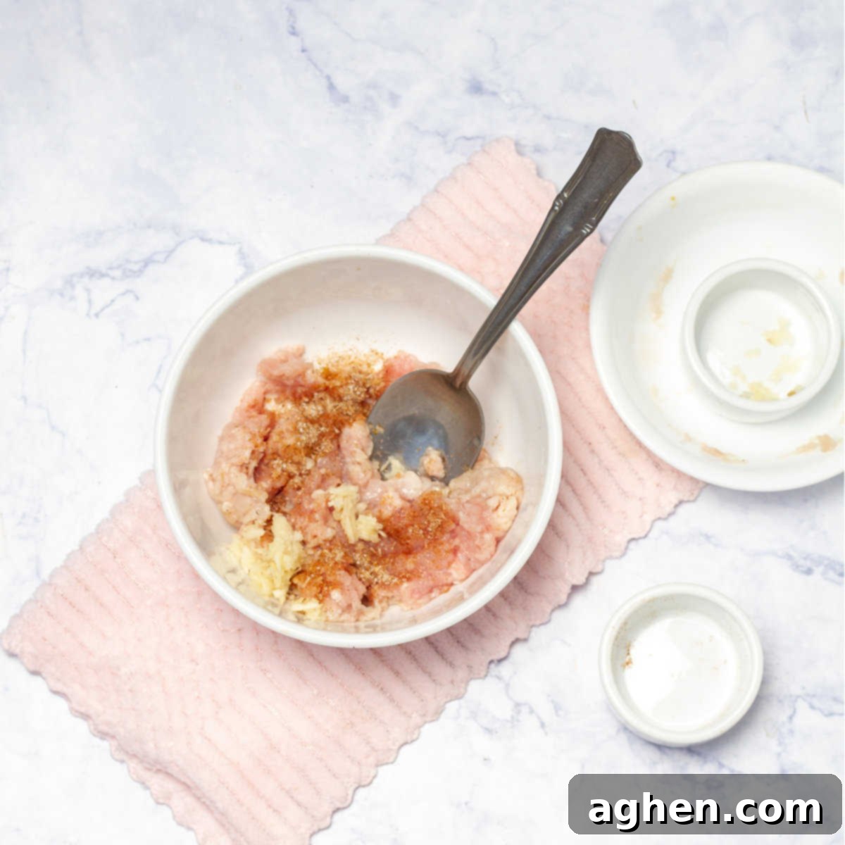 Ground turkey breast being seasoned with salt, pepper, garlic, and taco seasoning in a mixing bowl.
