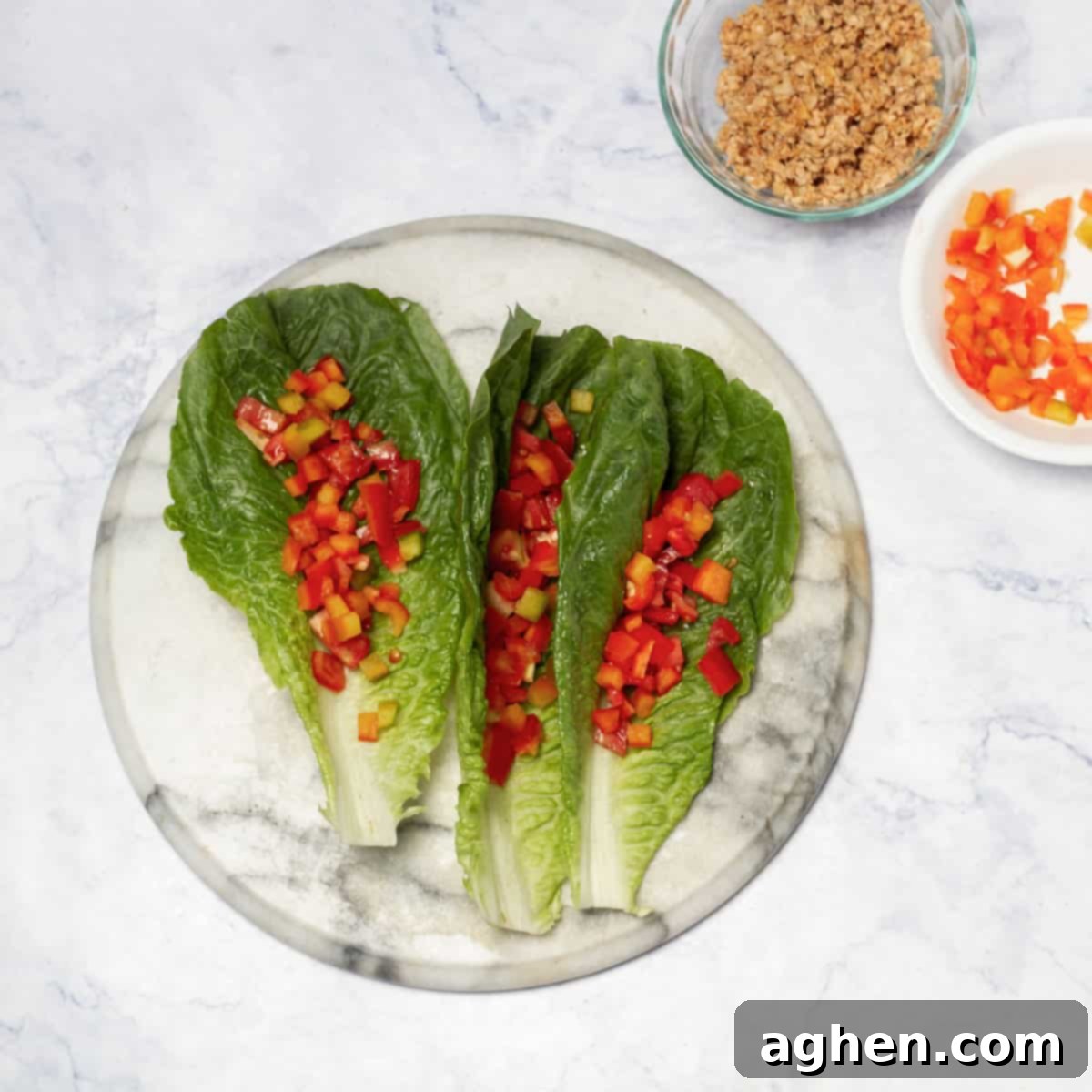 Fresh romaine lettuce leaves arranged on a platter alongside bowls of prepared diced vegetables and cottage cheese.