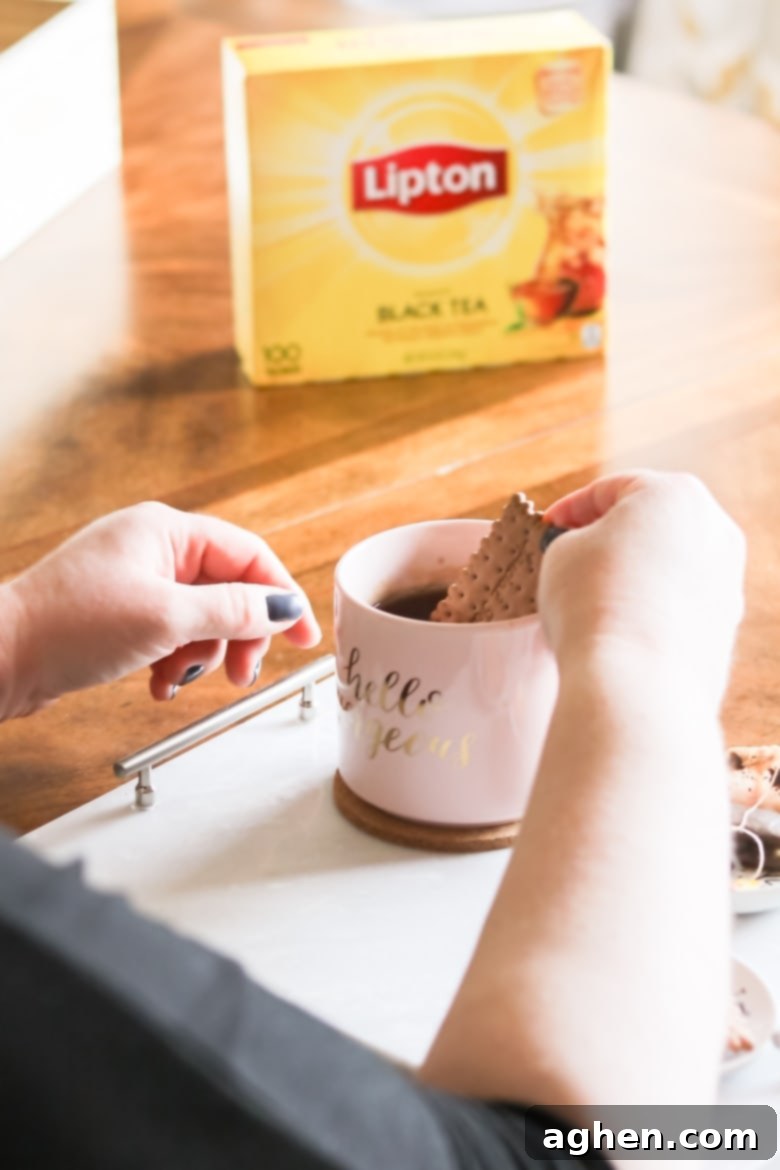 dunking a tea biscuit in a mug of Lipton Black Tea. The box of Lipton Tea is in the background.