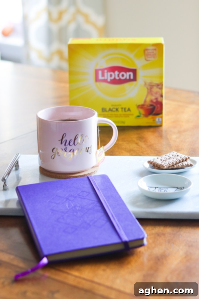 Hello Gorgeous pink coffee mug, purple notebook, and tea biscuits on a tray with a box of Lipton tea in the background.