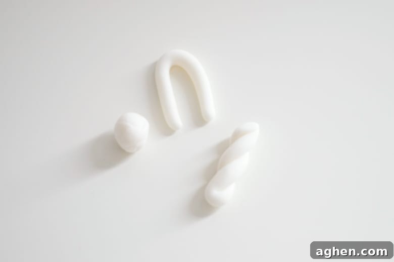 white fondant in a small ball, white fondant rolled into a U shape, and white fondant twisted to form a unicorn horn