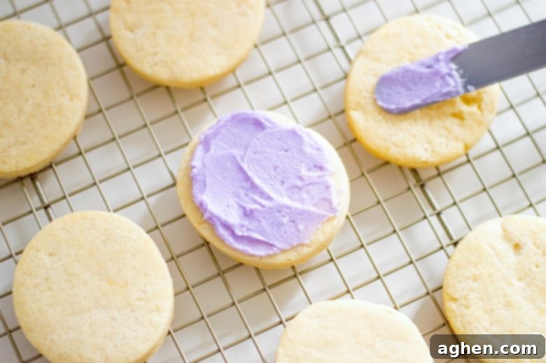 An offset spatula icing cookies on a cooling rack