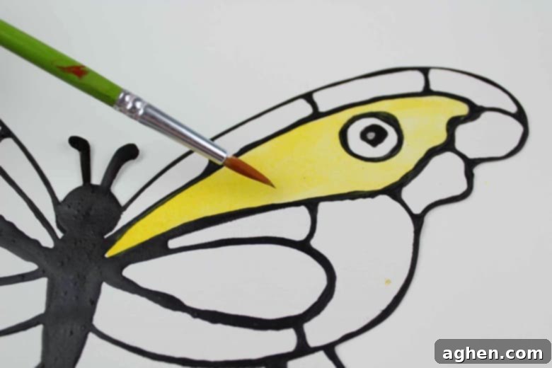 A paintbrush applying yellow paint to butterfly
