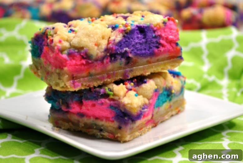 These unicorn bars are a delicious mix between sugar cookies and cheesecake and they are decorated to give them a magical unicorn look, featuring vibrant pink, purple, and blue swirls.