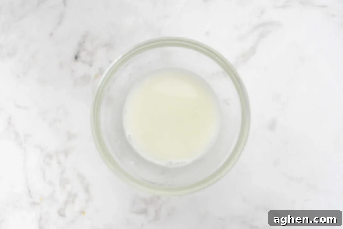 A small, clear bowl containing a white, cloudy cornstarch slurry, ready for mixing.