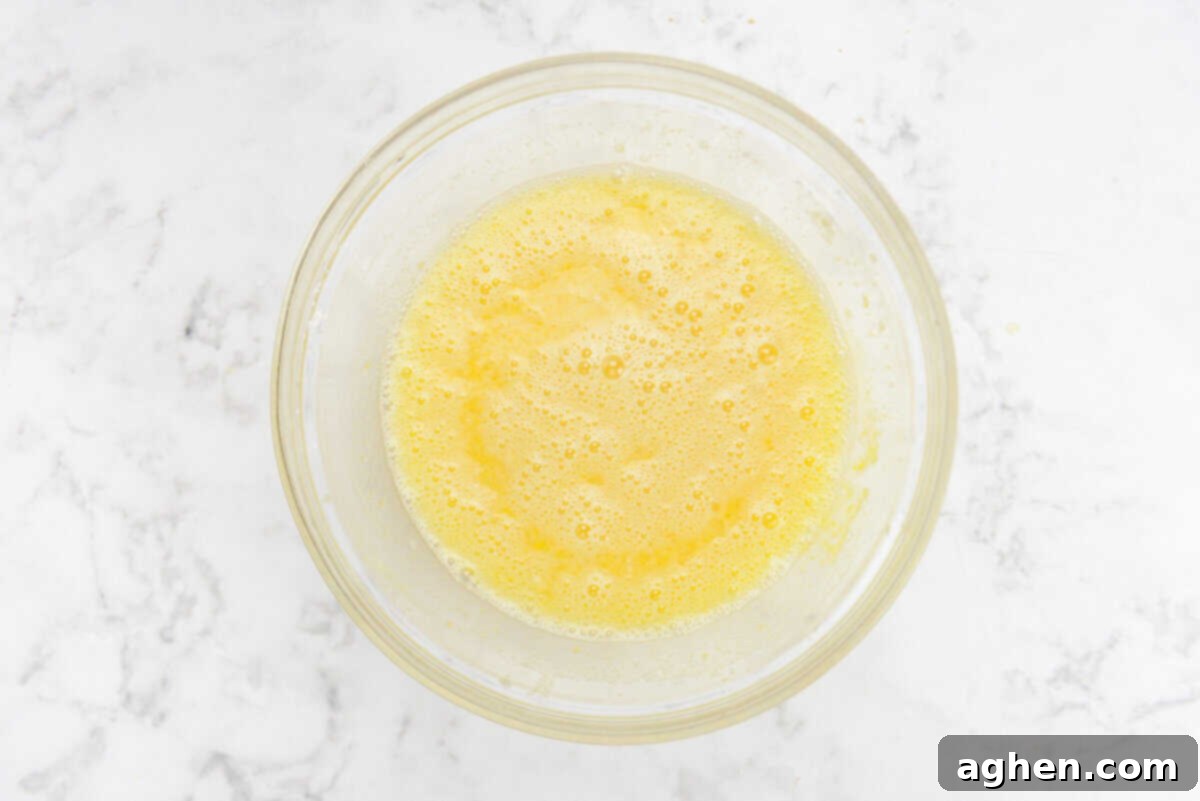 A large clear bowl with the whisked lemon filling