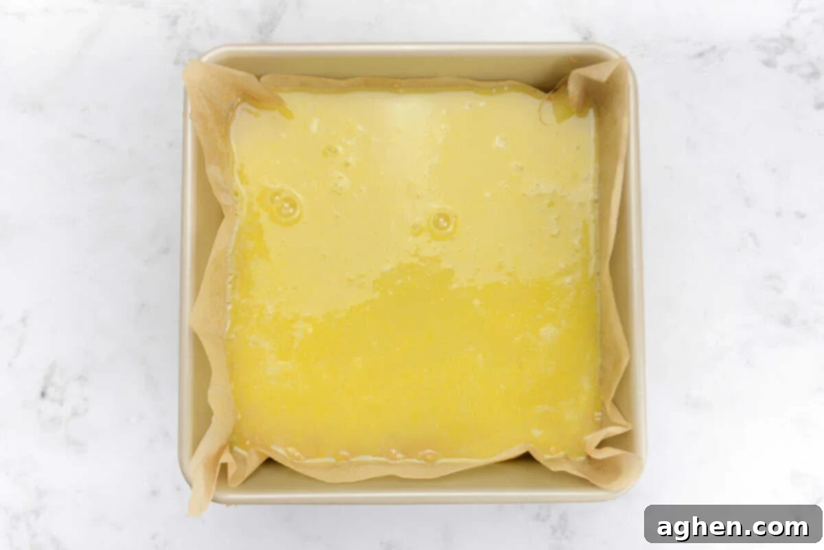 A gold baking pan with the yellow filling on top of the crust before baking