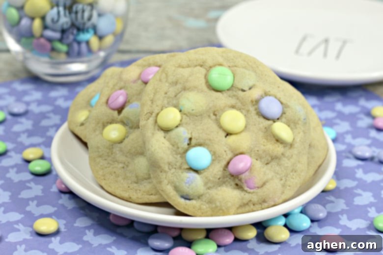 Large cookies with pastel M&Ms, served on a white plate.