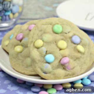 Large cookies with pastel M&Ms, served on a white plate.