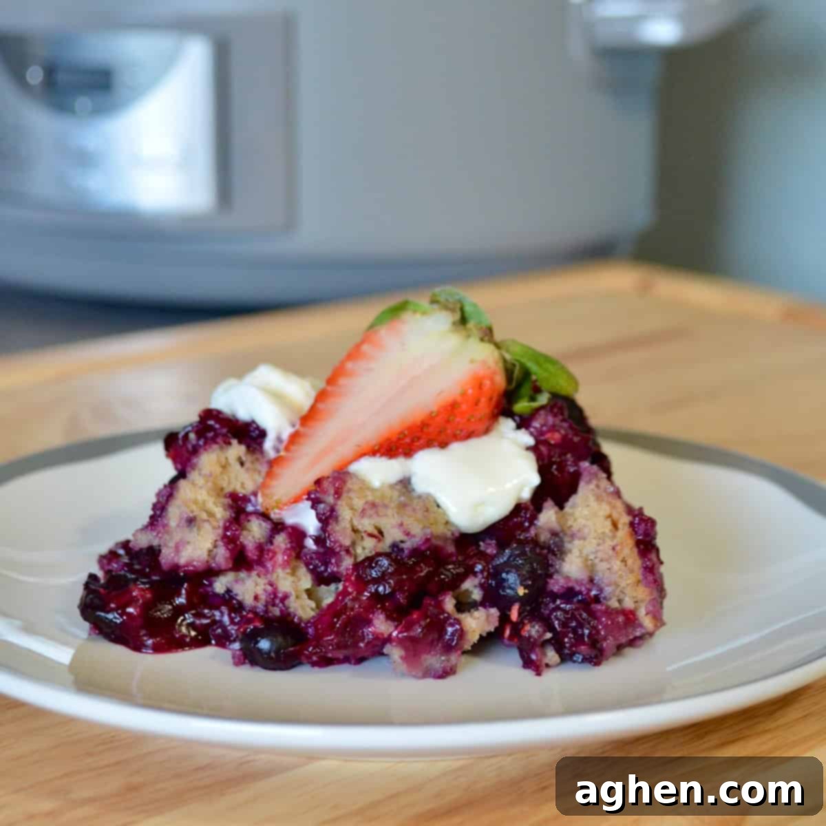A serving of freshly baked fruit cobbler, garnished with a ripe strawberry on a white plate.