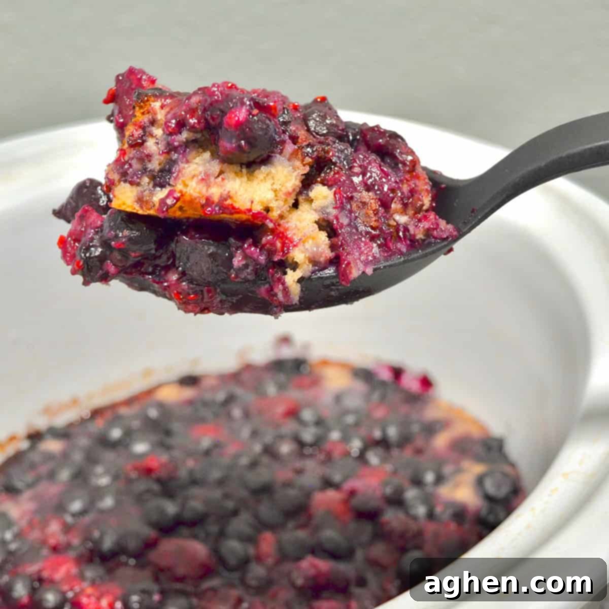 A scoop of warm, freshly baked fruit cobbler with a perfect crust, ready to be served.