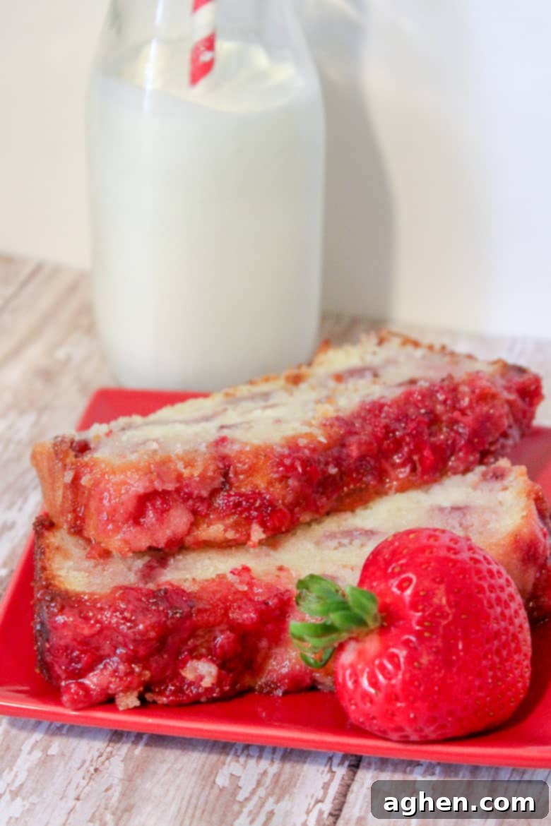 2 slices of strawberry pound cake on a red plate with a strawberry on the side. A glass of milk with a red and white straw is in background.