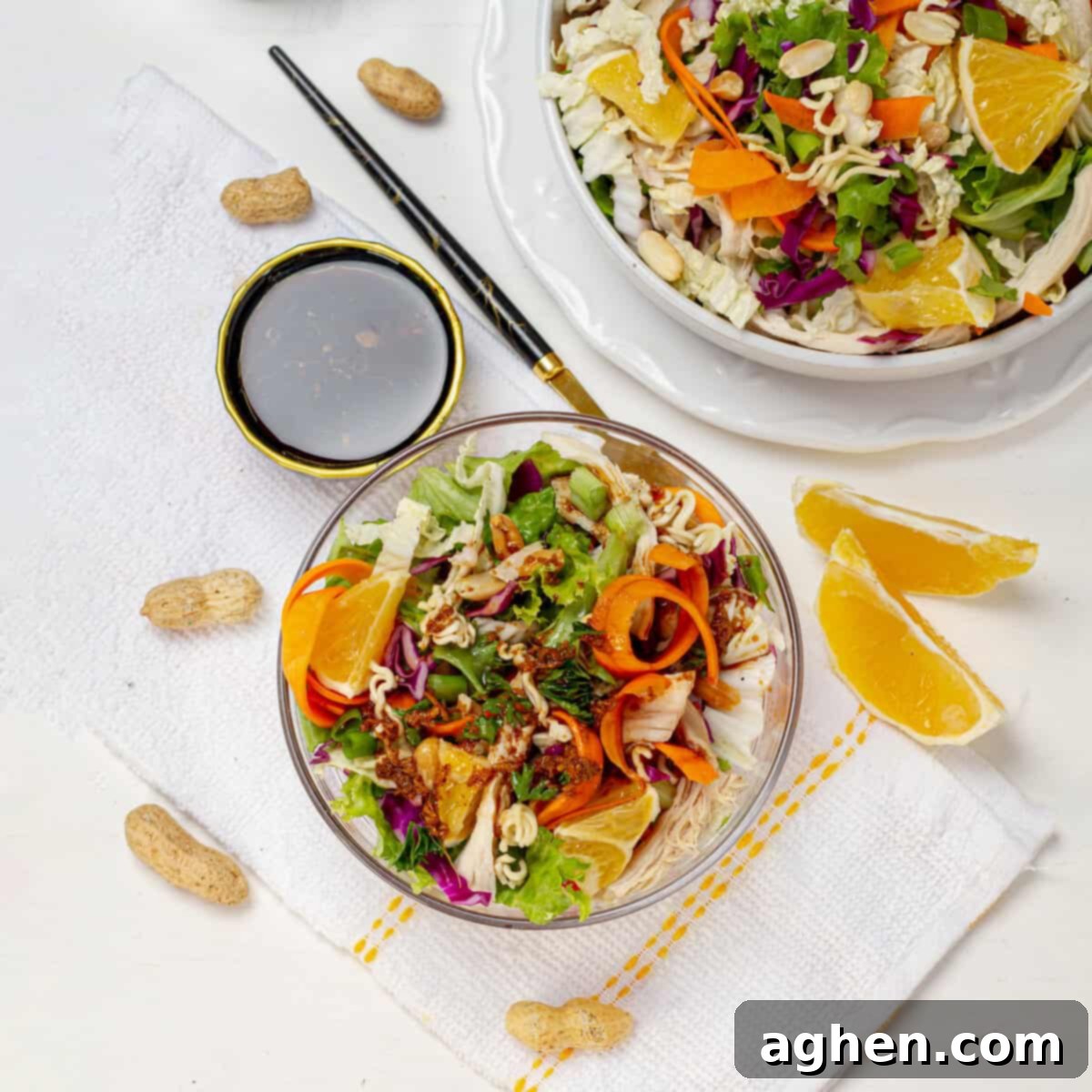 Chinese Chicken Salad served in two bowls, garnished with peanuts and fresh herbs.