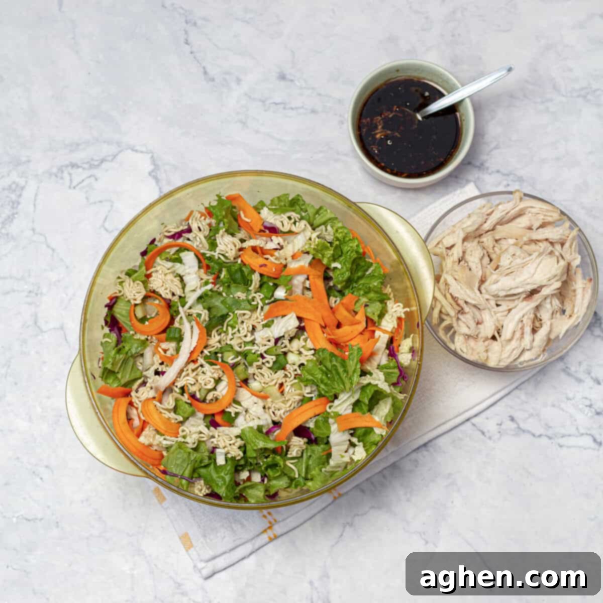 A large mixing bowl containing shredded cabbage, carrots, lettuce, and sliced scallions.