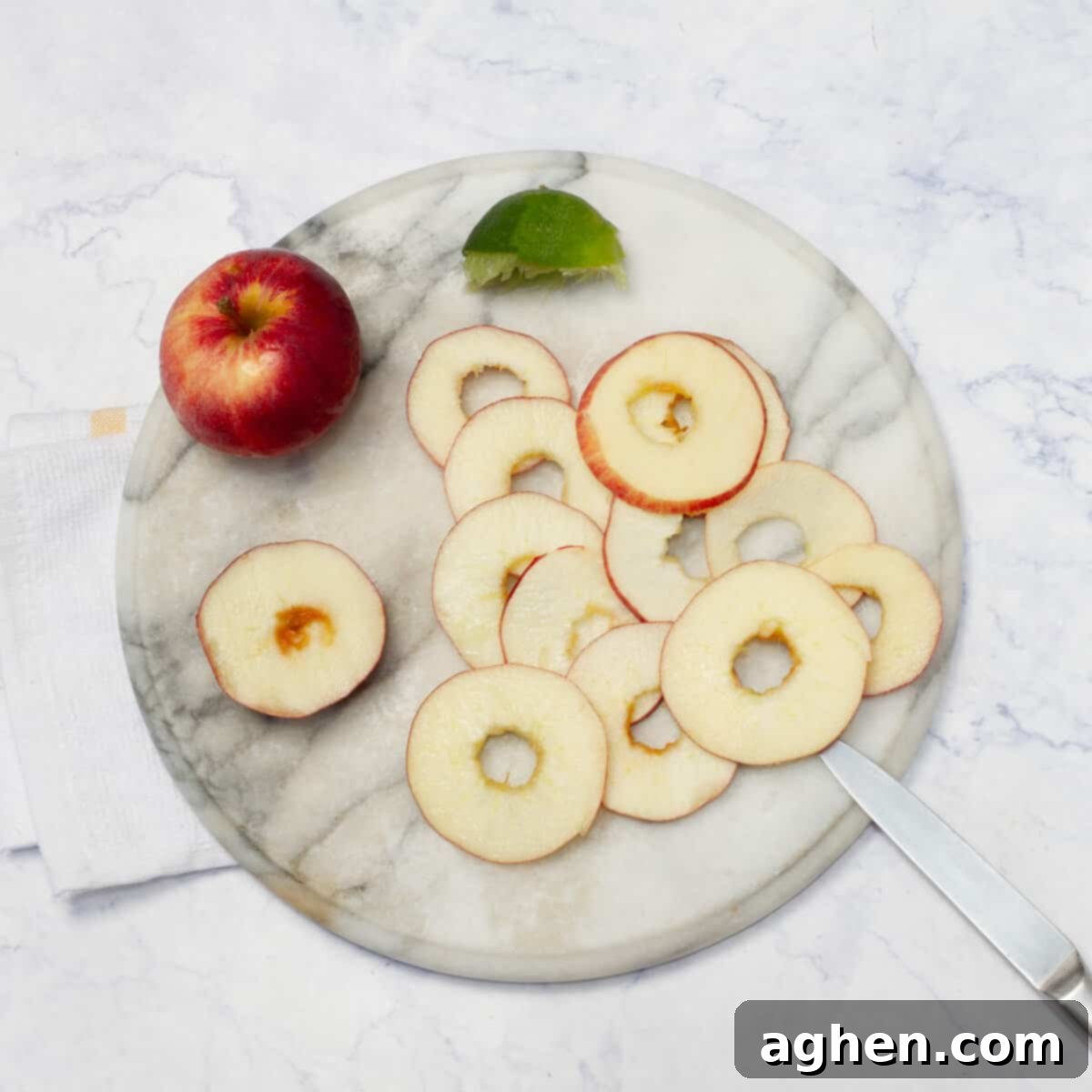 Thinly sliced apples next to a whole apple on a wooden board
