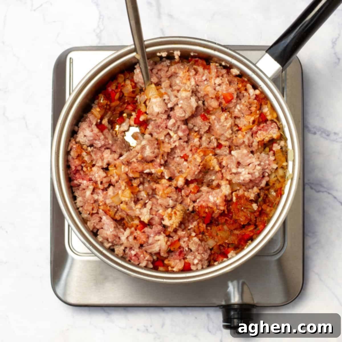 Ground pork browning in a skillet with sautéed vegetables, forming a rich Napolitan sauce base.