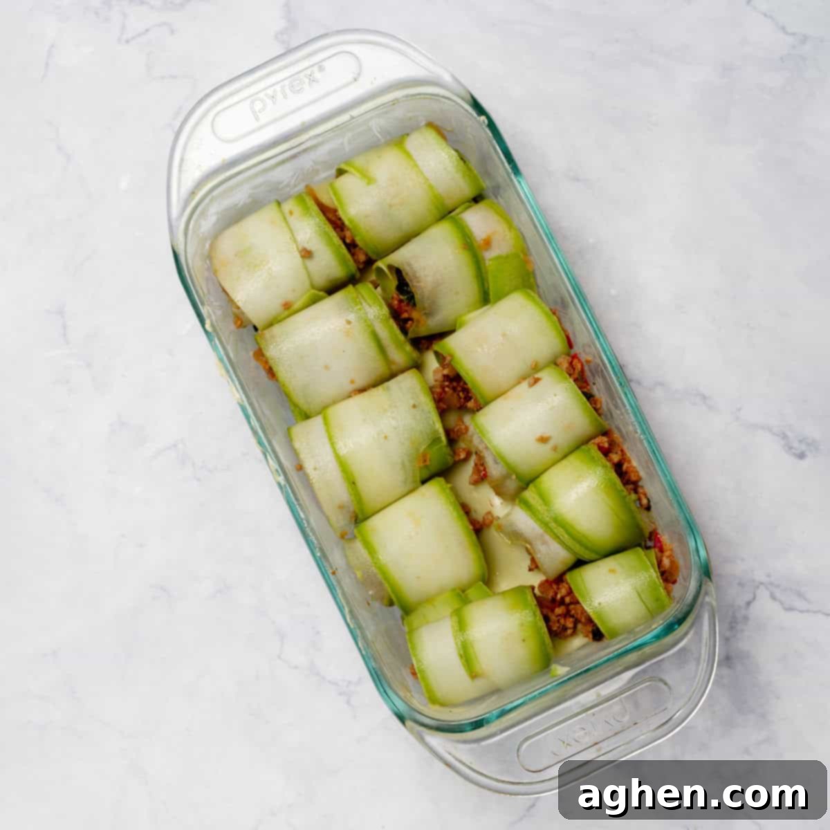 Zucchini Cannelloni rolls neatly arranged in a baking tray, ready for the oven.